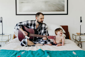 Dad plays guitar for baby in plaid kimono robe