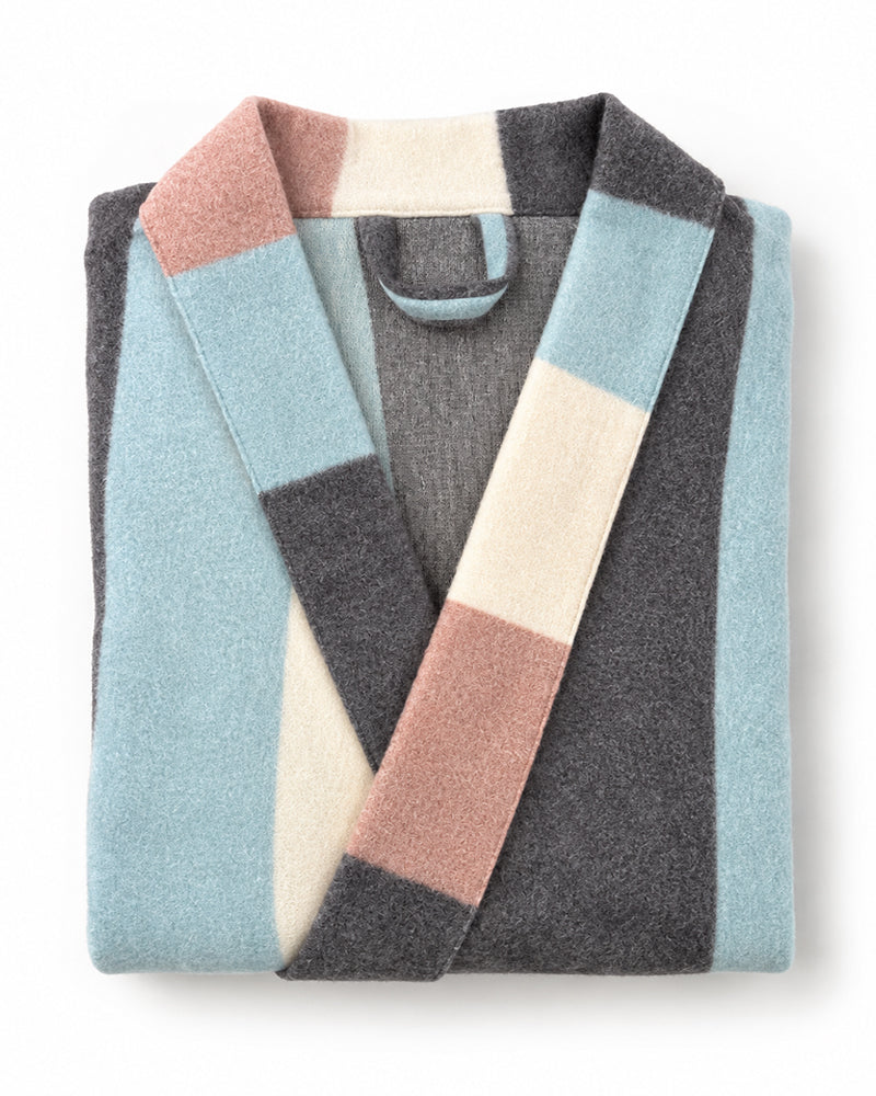 A folded knit robe with a color-block pattern in light blue, charcoal gray, cream, and dusty pink, shown on a clean white background.