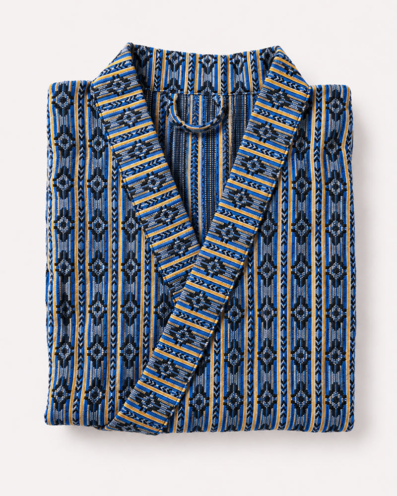 Folded blue and yellow patterned robe on a white background